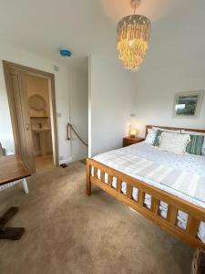 a bedroom with a large bed and a chandelier at Sunset View - Luxury accommodation in the Cotswolds in Tewkesbury