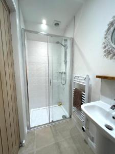 a white bathroom with a shower and a sink at Sunset View - Luxury accommodation in the Cotswolds in Tewkesbury