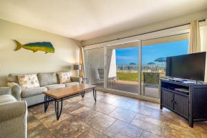 a living room with a couch and a tv at Beach House Condominiums C103 - Beachfront with Pool, Wi-Fi, & Beach Service in Destin +29 photos