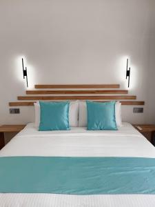 a white bed with two blue pillows on it at Boli Dhigurah in Dhigurah