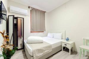 a white bedroom with a bed and a table at Agora Park Hotel in İzmir