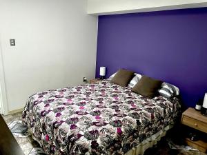 a bedroom with a bed with a purple wall at Departamento Independiente a 2 cuadras de Costanera in Punta Arenas