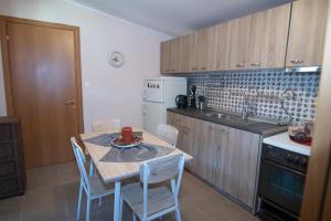 a kitchen with a table and chairs and a white refrigerator at KALLIOPIs HOUSE in Paralia Katerinis