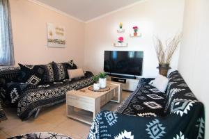 a living room with a couch and a tv at KALLIOPIs HOUSE in Paralia Katerinis