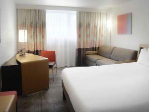 a hotel room with a bed and a couch at Novotel Caen Côte de Nacre in Caen +69 photos