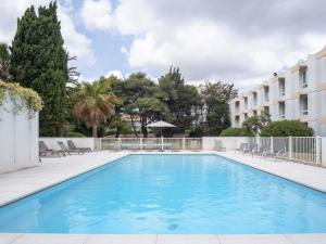 a swimming pool in front of a building at Novotel Narbonne Sud A9/A61 in Narbonne