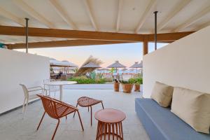 a patio with a blue couch and chairs and tables at Aptera Beach in Amoudara Herakliou