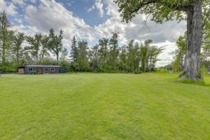 a large grass field with a house in the background at On the Flathead River! Rustic Saloon-Themed Cabin in Columbia Falls