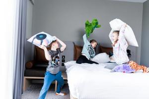 two children are playing with pillows on a bed at Moxy Slough in Slough