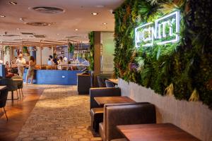 a restaurant with a green wall with tables and chairs at The Tower Hotel, by Thistle in London