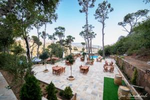 an outdoor patio with tables and chairs and trees at Beel Hills in Khallat al Mutayn