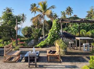 a patio with benches and tables and palm trees at Villa D40 in Weligama