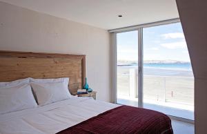 ein Schlafzimmer mit einem Bett mit Blick auf den Strand in der Unterkunft Oceano Patagonia in Puerto Pirámides