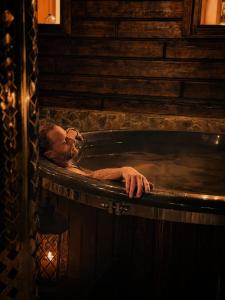 a man laying in a bath tub with his head in it at Forest Camp Dom w Górach Sowich in Michałkowa