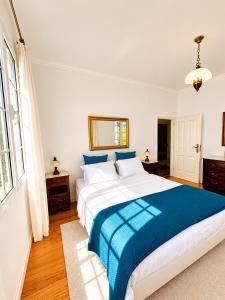 a bedroom with a large bed with a blue blanket at A Velha Casa Caboz in Ponta do Sol +16 photos