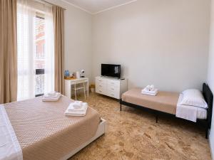 a bedroom with two beds and a tv and a window at Alba Mediterranea in Reggio di Calabria +6 photos