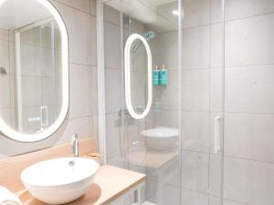 a white bathroom with a sink and a shower at Novotel Rouen Sud Zenith Parc Expo in Saint-Étienne-du-Rouvray