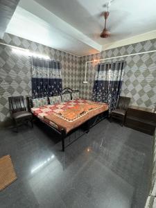 a bedroom with a bed and two chairs in it at ROGHAY COTTAGE in Matheran