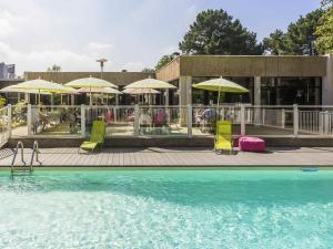 a pool with chairs and umbrellas on a patio at ibis Styles Lorient Caudan in Caudan