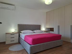 a bedroom with a large bed with a pink blanket at Vacation home, Ferienhaus KLAUDIA in Kraj, Mošćenička Draga near Opatija in Mošćenička Draga