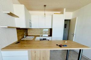 a kitchen with white cabinets and a wooden counter top at Lacanau-Océan Triplex Front de mer in Lacanau-Océan +15 photos