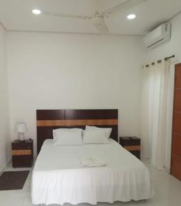 a bedroom with a white bed with a wooden headboard at Hospedaje Alexa in Asunción