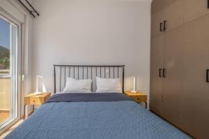 a bedroom with a blue bed with two lamps and a window at Blue Skala - Indigo Apartment I in Skala