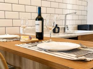 a table with two wine glasses and a bottle of wine at Welkom Woord - Aluguel Flats e Aptos curta temporada - Entrada com senha in Holambra