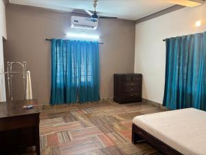 a bedroom with blue curtains and a bed and a dresser at Oceanbliss Villa in Pallipuram +12 photos