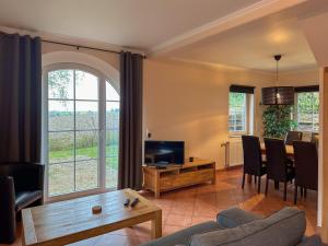 a living room with a couch and a tv and a table at Landhuis Schneifel in Brandscheid