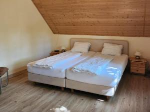 a large bed in a room with a wooden ceiling at Landhuis Schneifel in Brandscheid