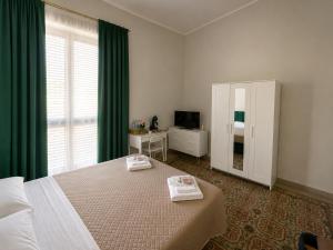 a bedroom with a bed with green curtains and a television at Alba Mediterranea in Reggio di Calabria