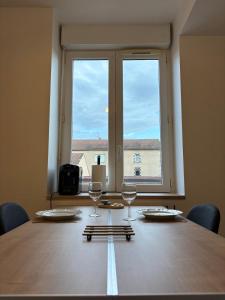 a table with two wine glasses and a large window at Cocon de la gare in Montélimar