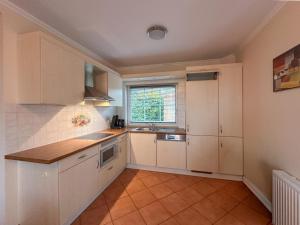 a kitchen with white cabinets and a sink and a window at Landhuis Schneifel in Brandscheid +6 photos