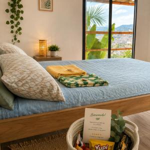 a bedroom with a bed with blue sheets and a window at ECOHostal Las Hamacas Rincon Del Árbol in Villamaría