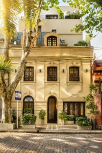 a yellow building with a tree in front of it at Miravida Soho Hotel & Wine Bar in Buenos Aires