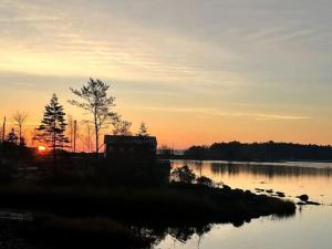 a house on the shore of a lake at sunset at Private Oceanfront Suite Hot Tub & Fireplace in Lunenburg
