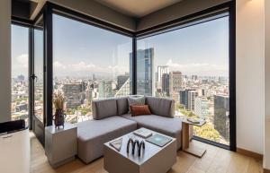 a living room with a couch and large windows at University Tower by Kukun Apartments in Mexico City