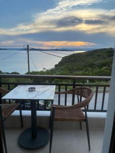 a table and chairs on a balcony with a view of the ocean at Thanos ,Rooms and Apartments in Ouranoupoli