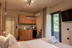 a bedroom with a white bed and a kitchen at Montiva GuestHouse in Karpenisi
