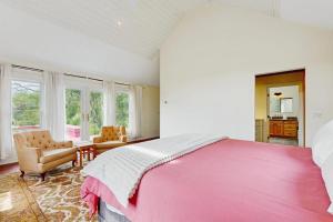 a bedroom with a large pink bed and chairs at High Street Retreat in Cavendish