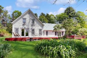 a white house with a red fence in the yard at High Street Retreat in Cavendish