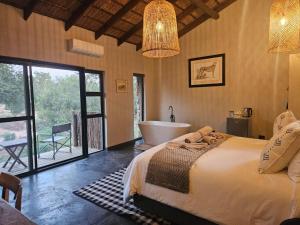 a bedroom with a bed and a tub and a bathroom at Nkinga River Lodge in Balule Game Reserve