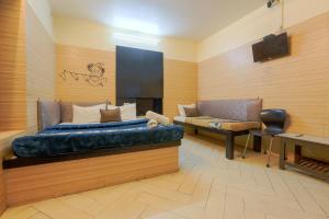 a bedroom with a bed and a couch and a piano at Hotel Shrimmaya, Ujjain in Ujjain