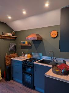 a kitchen with blue cabinets and a stove and a sink at Tranquil Off-Grid Cabin in Ballina