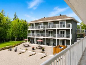 a large house with a balcony and tables and chairs at Escarpment Heights Motel in Tobermory