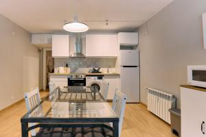a kitchen with a glass table and a stove and refrigerator at Apartamento Duplex en La Molina in Alp