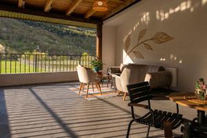 a patio with chairs and a table and a large window at Anne's Hotel in Mestia in Mestia