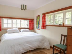 a bedroom with a white bed and two windows at Culearn Mill in Lochearnhead