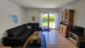 a living room with a black couch and a tv at Haus Uns Moi Hus in Krummhörn